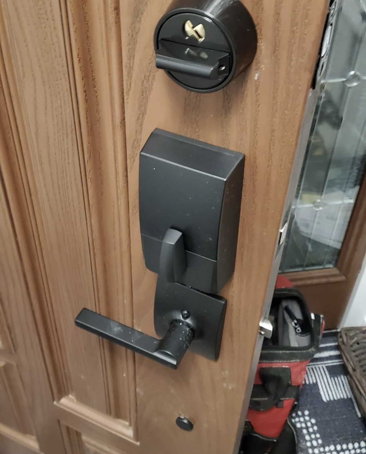 New black keypad smart lock and deadbolt installed on a wood front door